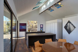 Offene Küche mit Essbereich in hohem Raum mit Oberlicht und Terrassenzugang