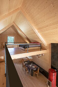 Loft mit heller Holzverkleidung, Galerie-Schlafbereich, unterhalb Esstisch und roter Kaminofen