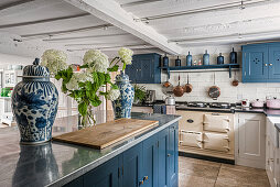 Country-style kitchen with blue cabinets and white flowers