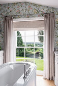 Badezimmer mit floraler Tapete und Ausblick auf den Garten