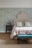 Schlafzimmer mit geblümten Tapeten und klassischem Bettgestell