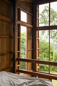 Schlafzimmer mit Bambusverkleidung und Blick in den Garten