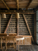 Esstisch aus Massivholz mit Stühlen und Bank, Bambuskonstruktion und Strohgeflecht im Hintergrund