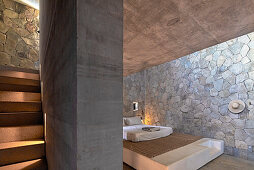 Bedroom with double bed, stone wall and concrete staircase in Mazunte, Mexico