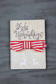 Wooden sign with Merry Christmas lettering and red and white bow