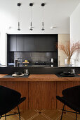 Modern kitchen with black cabinets, wooden table and pendant lights