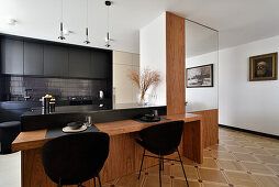 Moderne Küche mit schwarzen Fronten und Holztisch mit schwarzen Stühlen, Warschau, Polen