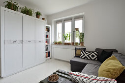 Bright living room with corner sofa and lots of houseplants