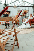 Autumnal decoration with dried flowers in a greenhouse, bridal couple in the background