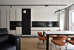 Moderne Küche in Schwarz-Weiß mit Esstisch und farbigen Designerstühlen