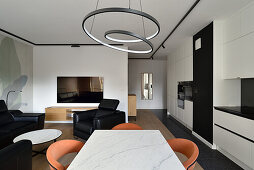 Modernes Wohn- und Esszimmer mit Ring-Pendelleuchte und schwarz-weißer Küchenzeile