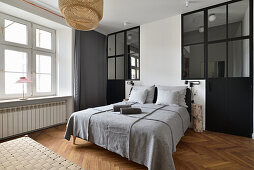 Modern eingerichtetes Schlafzimmer mit schwarzer Fenster-Trennwand