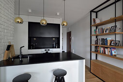 Modern kitchen with golden pendant lights, bar stools and bookshelf