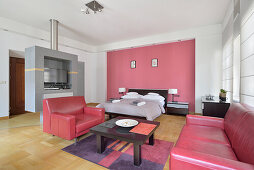 Modernes Studio-Apartment mit pinker Wand und roten Akzenten