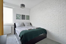 Schlafzimmer mit weißer Ziegelwand und dunkelgrünem Überwurf