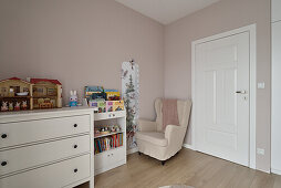 Children's room with toy shelf, white chest of drawers and reading chair