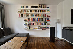 Living room with floating bookshelf, grey sofa and wooden floor