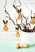 DIY Easter decoration: Bunny pendant made of wooden discs on branches in a white vase