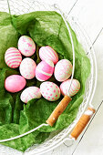 Painted Easter eggs in shades of pink and pink in a wire basket