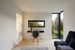 Arbeitszimmer mit Schreibtisch und Blick in den Garten, große Eckfenster