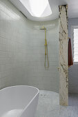 Modern shower area with marble partition wall and free-standing bathtub