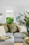 Bright living room with tropical cushions and eucalyptus bouquet in vase