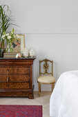 Antique wooden chest of drawers with decoration and chair in the bedroom