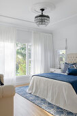 Bedroom with chandelier, stucco ceiling and blue and white bedspread