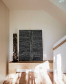 Wooden bench in the hallway with modern art and sculpture