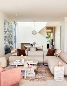 Bright living room with beige corner sofa and abstract mural