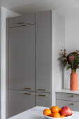 Grey fitted kitchen with golden handles and bouquet of flowers in modern vase