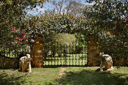 Garden gate with elephant statues and flowering climbing plants