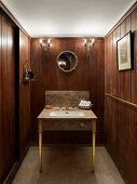 Washbasin in the guest WC with wood panelling and wall lamps
