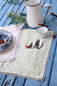 Self-sewn placemats with rose motif and ruffles on a blue wooden table