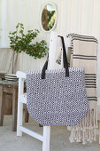 Self-sewn bag made from rag rug hangs on white chair