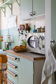 Retro kitchen area with green lacquered cupboards and vintage microwave