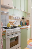 Compact kitchen with green lacquered cupboards and gas hob