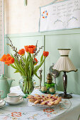 Tulips (Tulipa) in a vase on a laid kitchen table with retro lamp