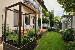 Garden with raised bed and terrace in front of a residential building