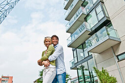 Paar umarmt sich vor einem modernem Wohnhaus, Hafencity Hamburg, Deutschland