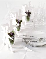 Papierfiguren und Blumen in Gläsern auf Hochzeitstisch