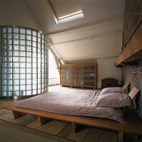 Dachloft mit Futon-Doppelbett und Bad ensuite hinter gebogener Wand aus Glasbausteinen