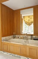 Eingebaute Badewanne mit Marmor-Einfassung und Holzvertäfelung mit integriertem Spiegel
