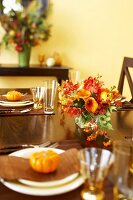 Herbstlich gedeckter Tisch mit Blumen und Zierkürbissen