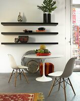 Baushaus-style white table and chairs in front of a black wall shelf