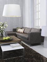 A sofa with a set of coffee tables and a white lamp shade in the corner of a living room