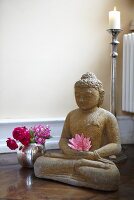 A Buddha statue and a vase of flowers in a yoga studio