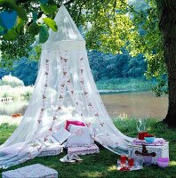 Floor cushions and decorative cushions under a romantic mosquito net by a lake