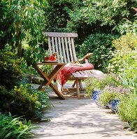 A wooden lounger and a table in a summery garden