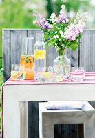 Fruit flavoured water and a bunch of flowers on a table outside